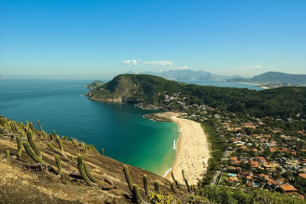 Foto de Niteró. Aparecem o céu azul, morros, residências e o mar