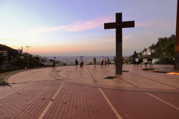Imagem da praça do Papa, em Belo Horizonte. Vê-se uma cruz, que marca o local da visita do Papa, e diversas pessoas tirando foto em no mirante.