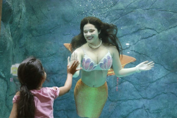 Imagem de menina brincando com sereia no Aquário de São Paulo