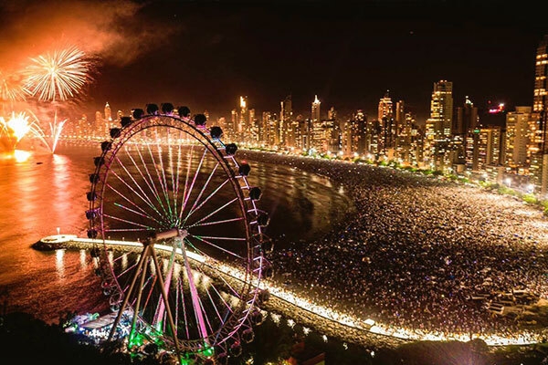 Imagem de centenas de pessoas na praia de Balneário na celebração do ano novo